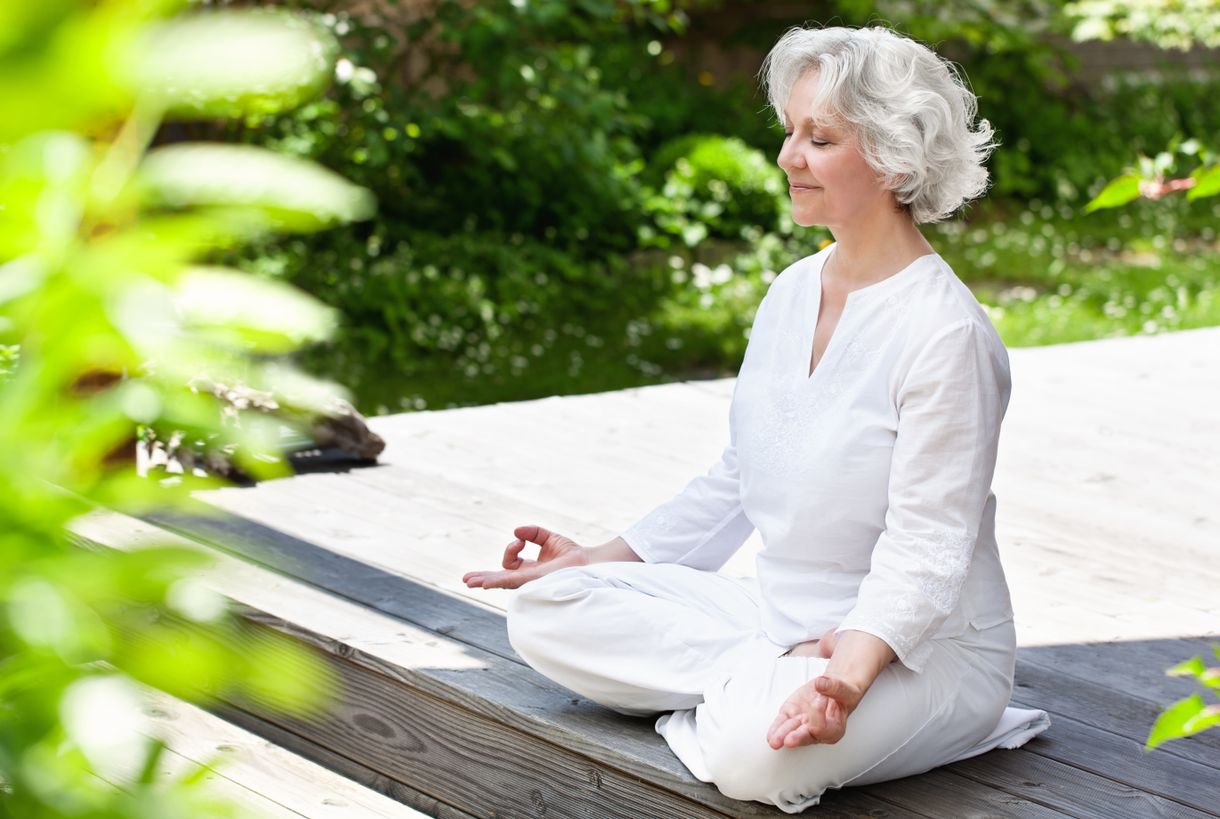 ältere Dame meditiert auf der Terrasse