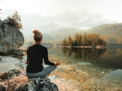 Eine Frau praktiziert Yoga am Eibsee mit Blick auf die Alpen