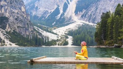 Eine Frau macht Yoga und meditiert auf einem Bergsee