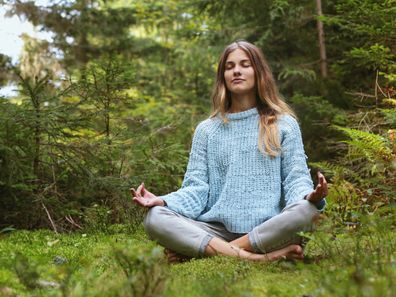Eine Frau meditiert im Wald
