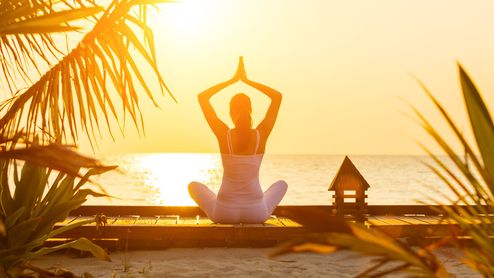 Junge Frau praktiziert Yoga bei Sonnenaufgang