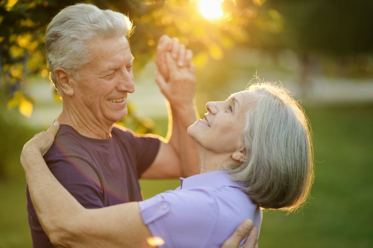älteres Paar tanzt im Garten im warmen Sonnenlicht