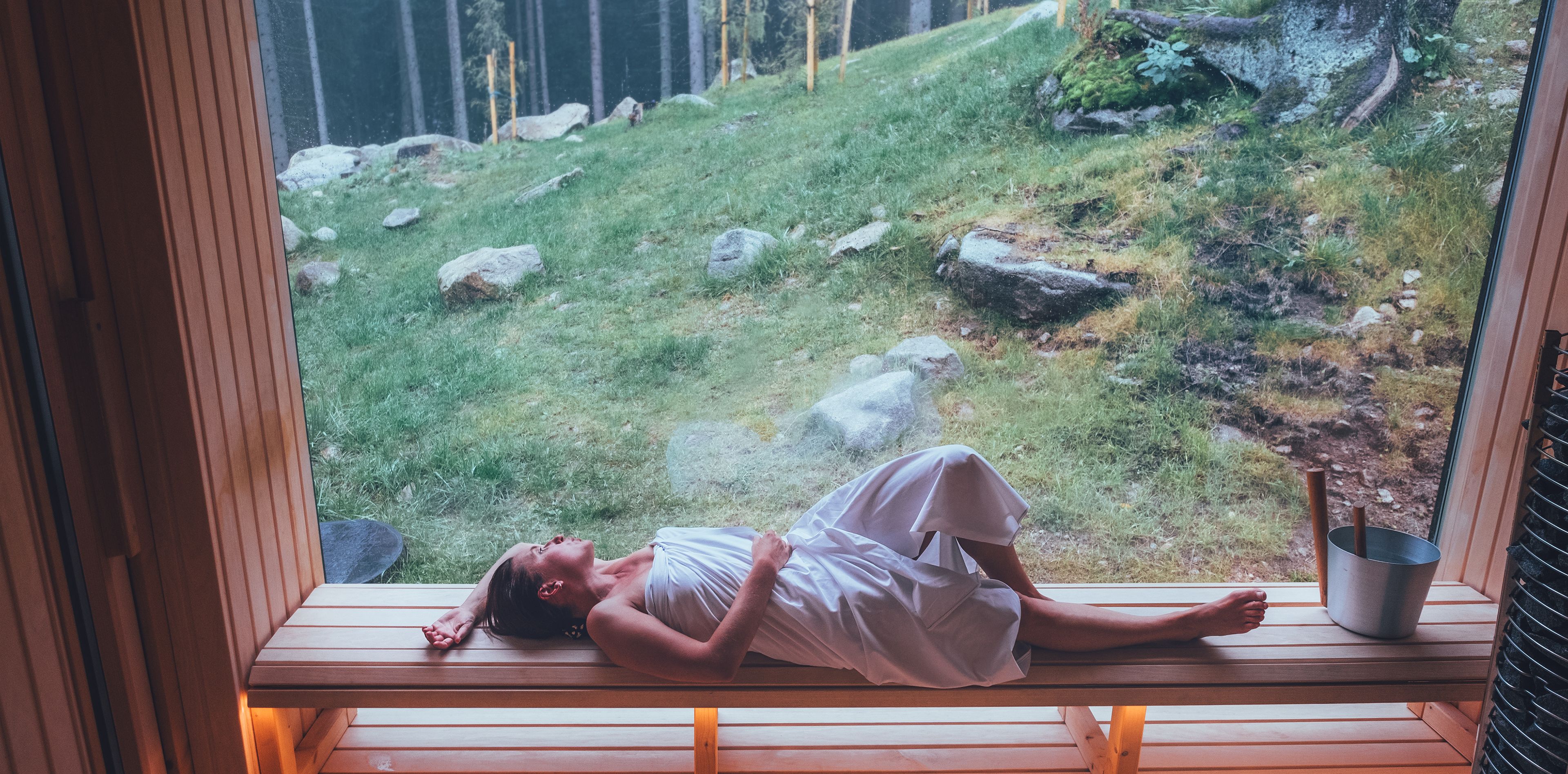 Frau liegt in Sauna mit Blick auf Berge