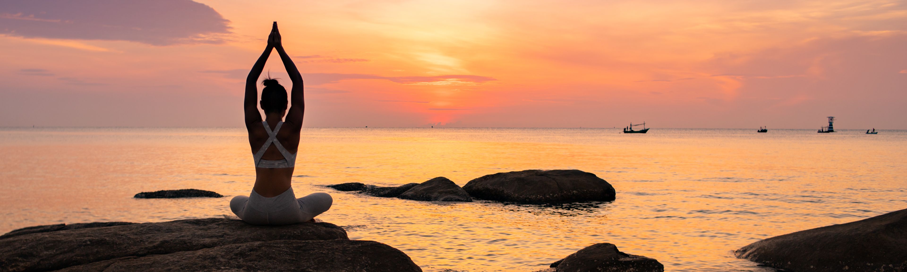 Frau meditiert auf Felsen am Meer