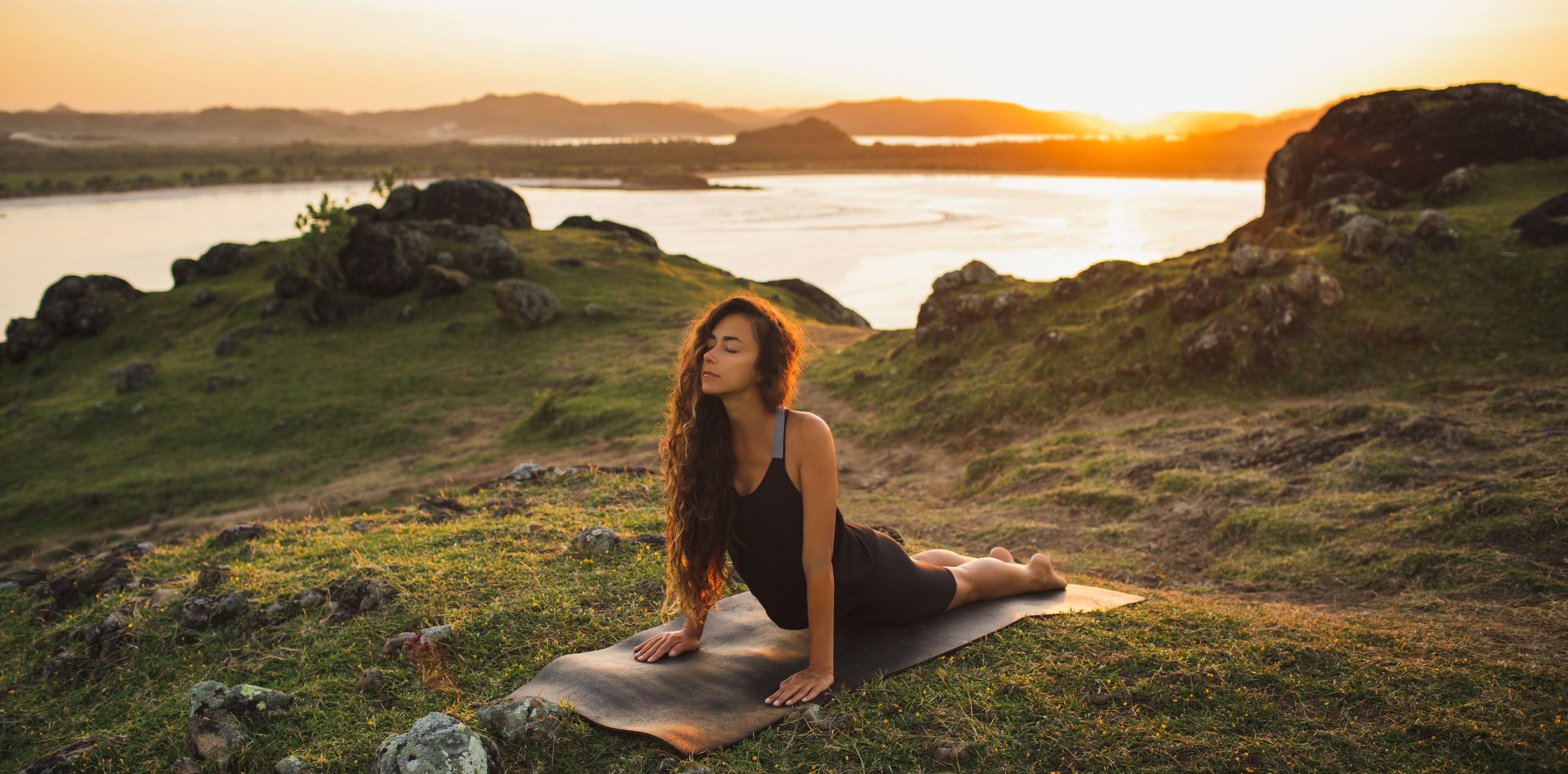 Frau beim Yoga an einem See bei Abendlicht