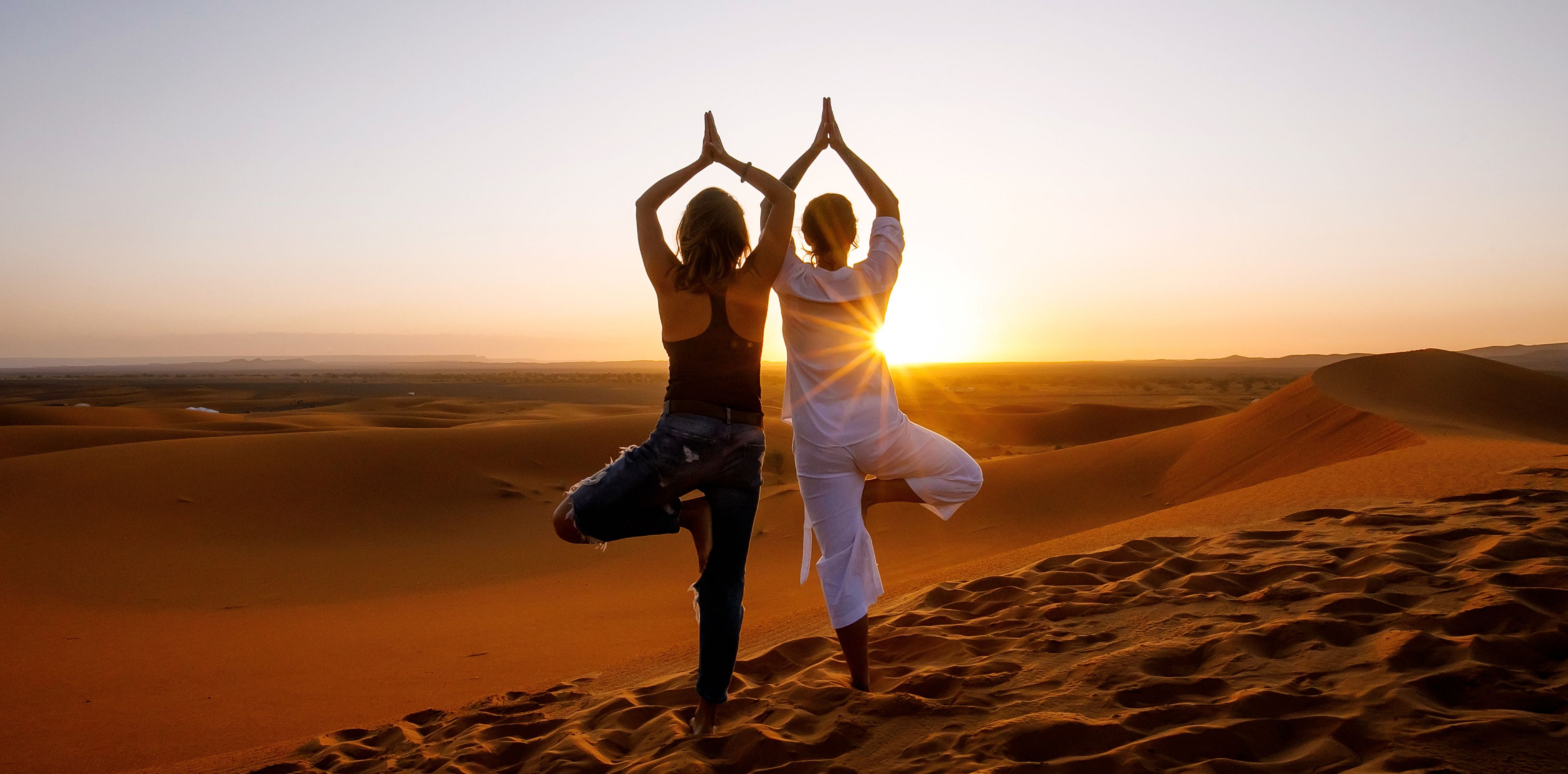 Zwei Frauen machen Yoga Posen in der Wüste
