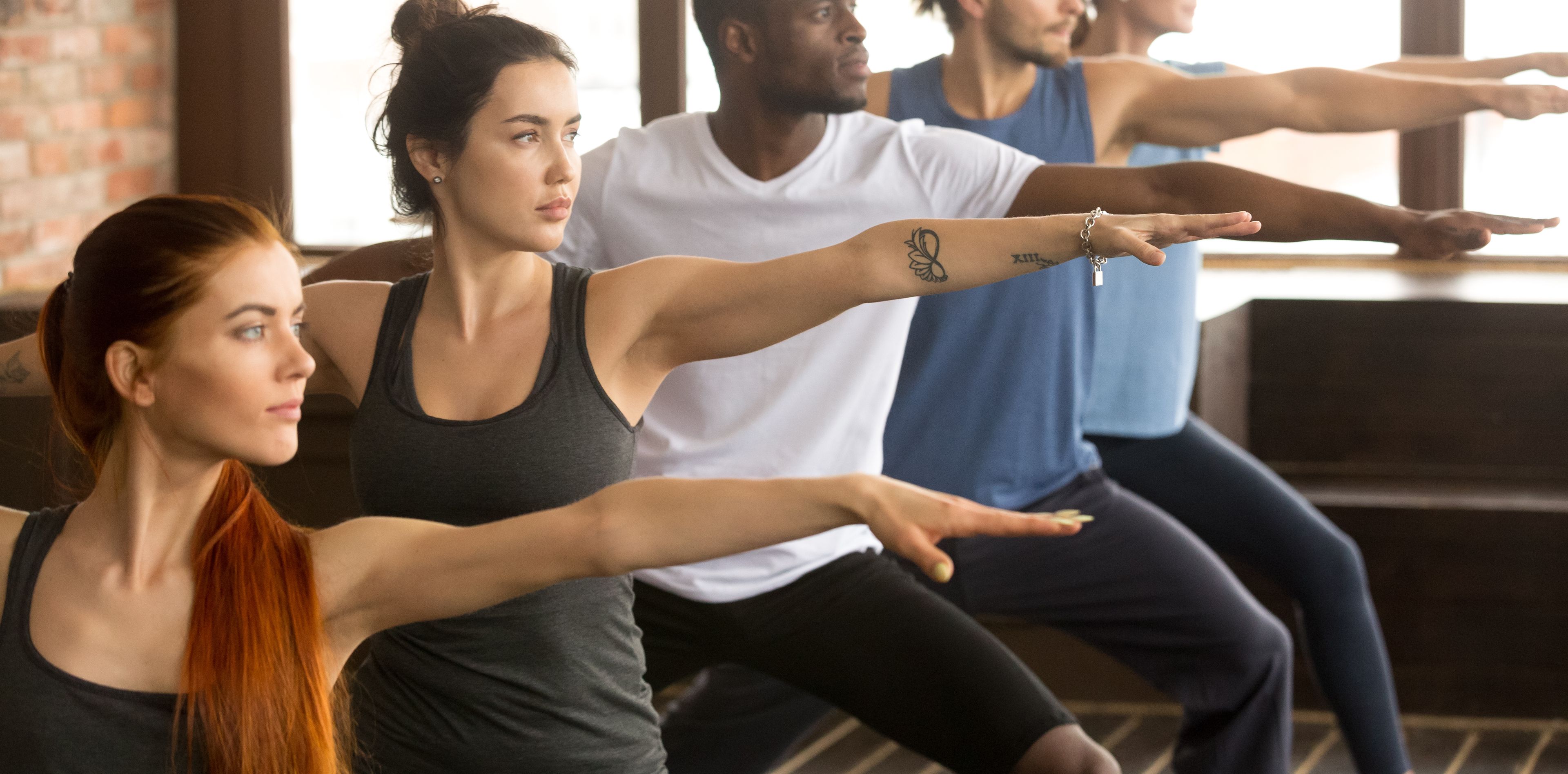 Mehrere Yogis führen nebeneinander die Krieger-Yoga-Pose aus
