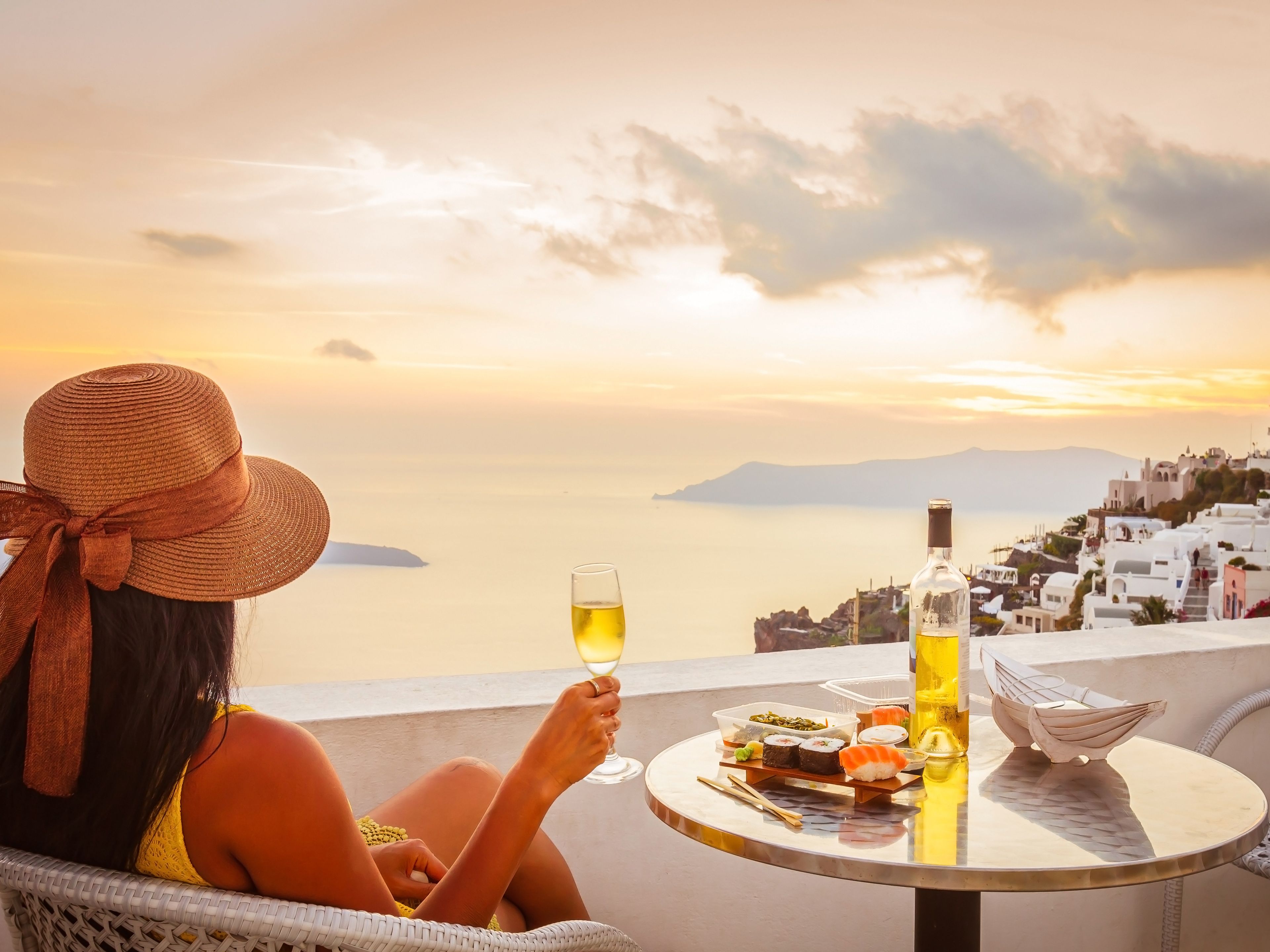 Una mujer se sienta en el balcón de su hotel en Santorini y disfruta de las vistas