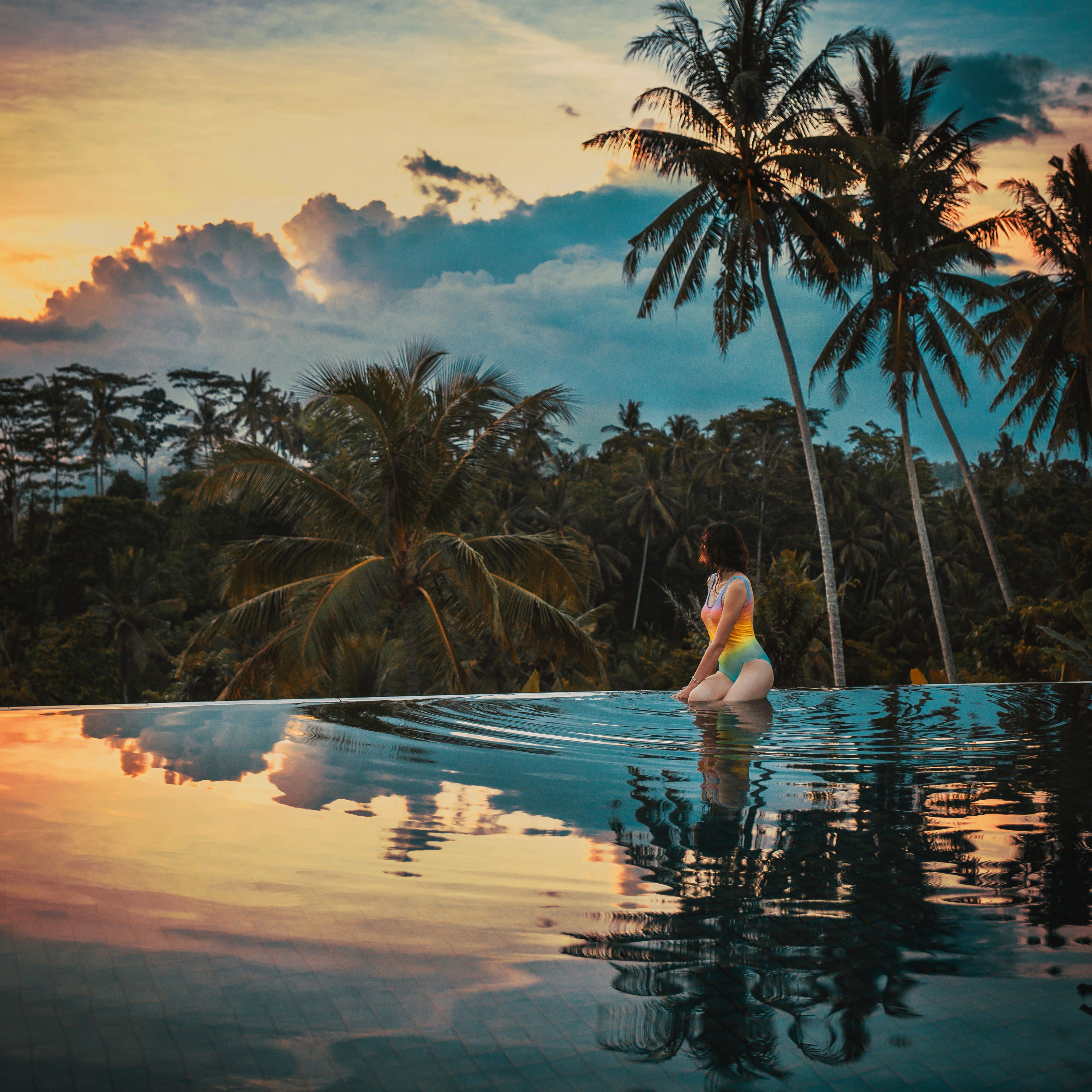 Woman in pool at sunset with jungle in background