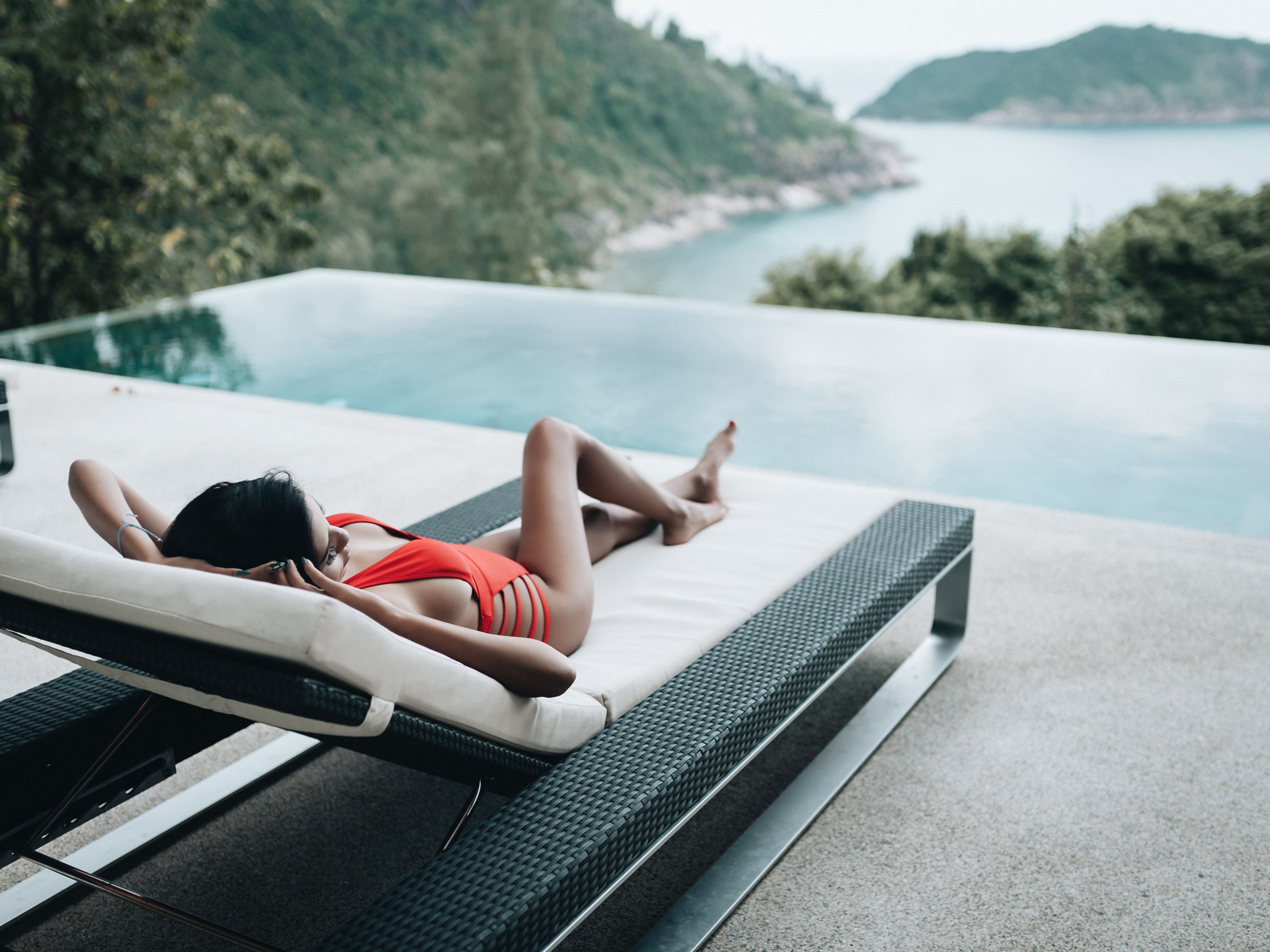 Una mujer se relaja en una tumbona frente a una piscina infinity en Tailandia