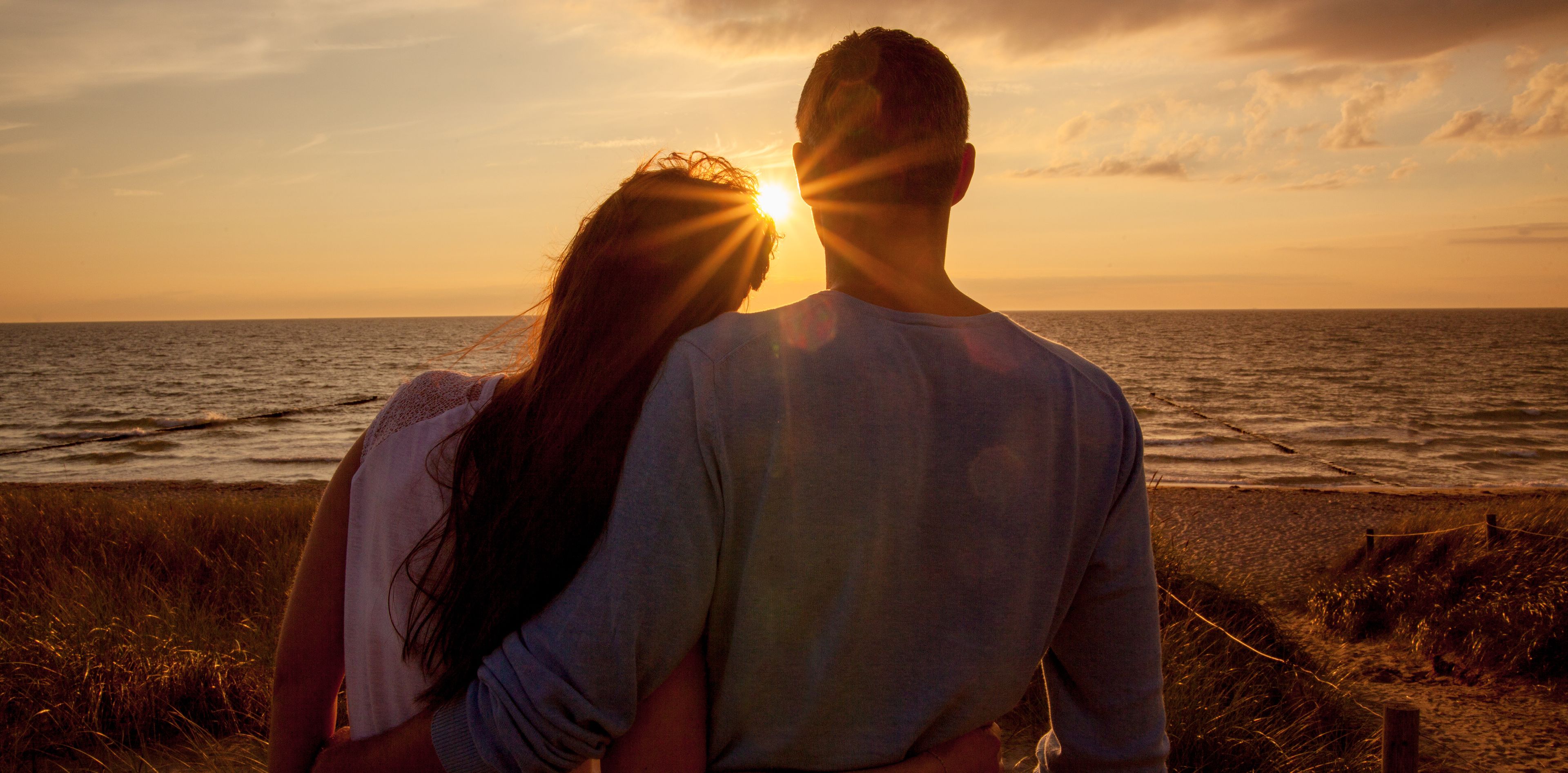 Paar während des Sonnenuntergangs im Arm am Strand