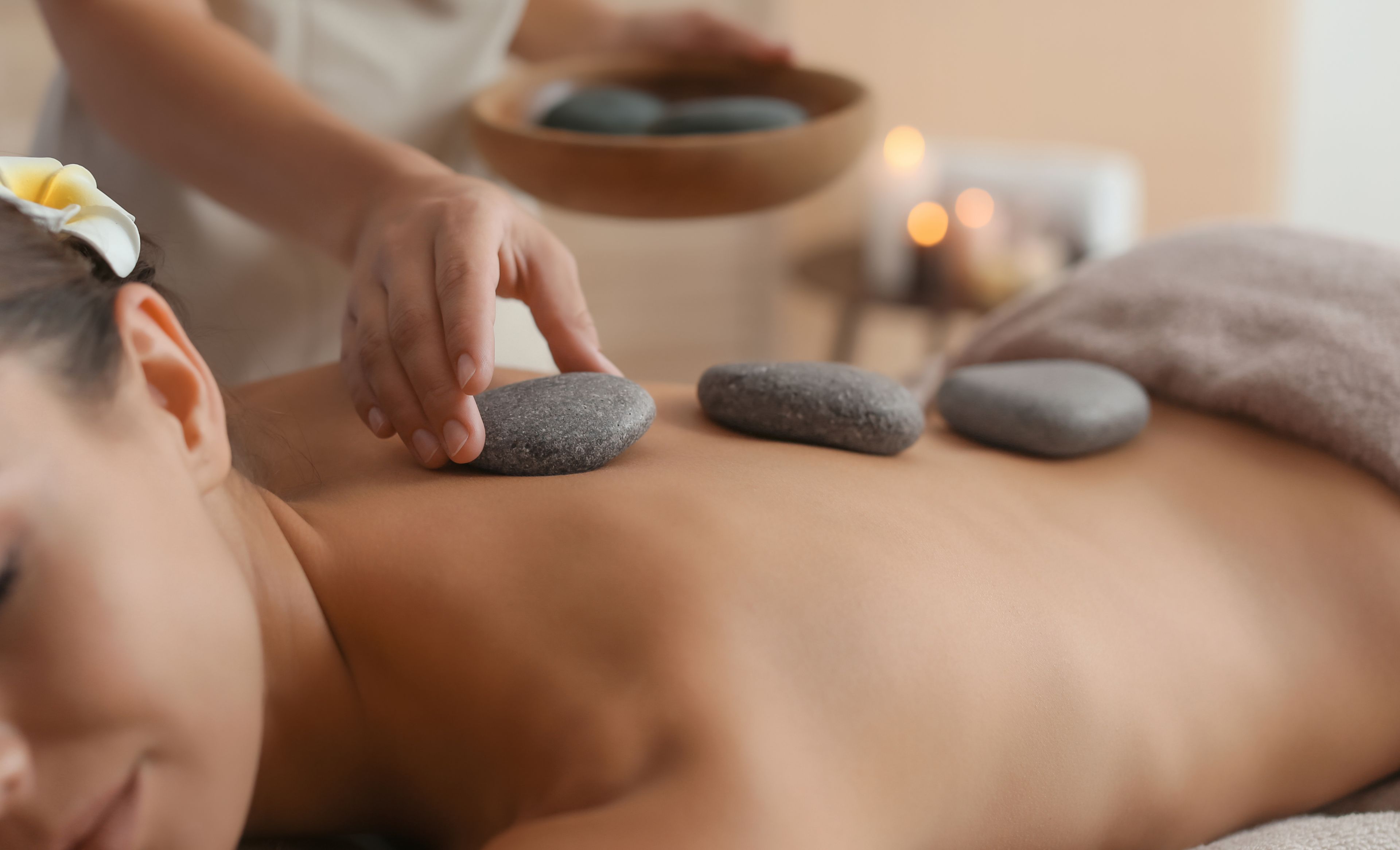 Una mujer haciéndose un masaje con piedras volcánicas