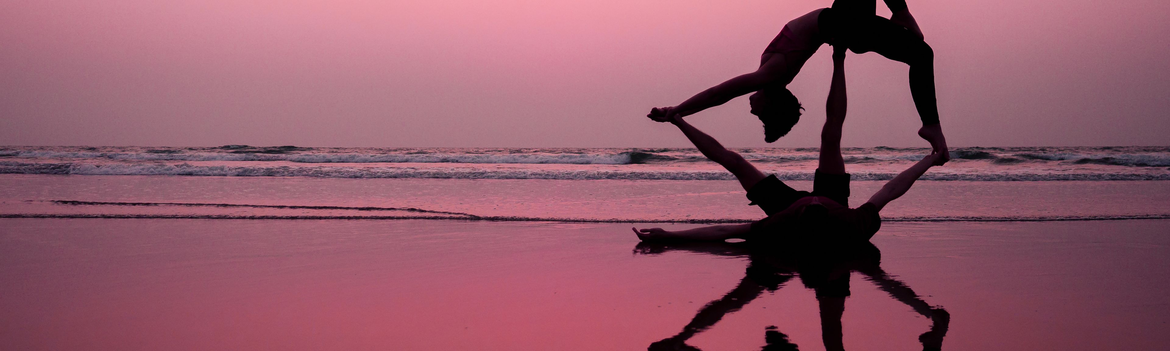Zwei Menschen am Strand beim Acro Yoga