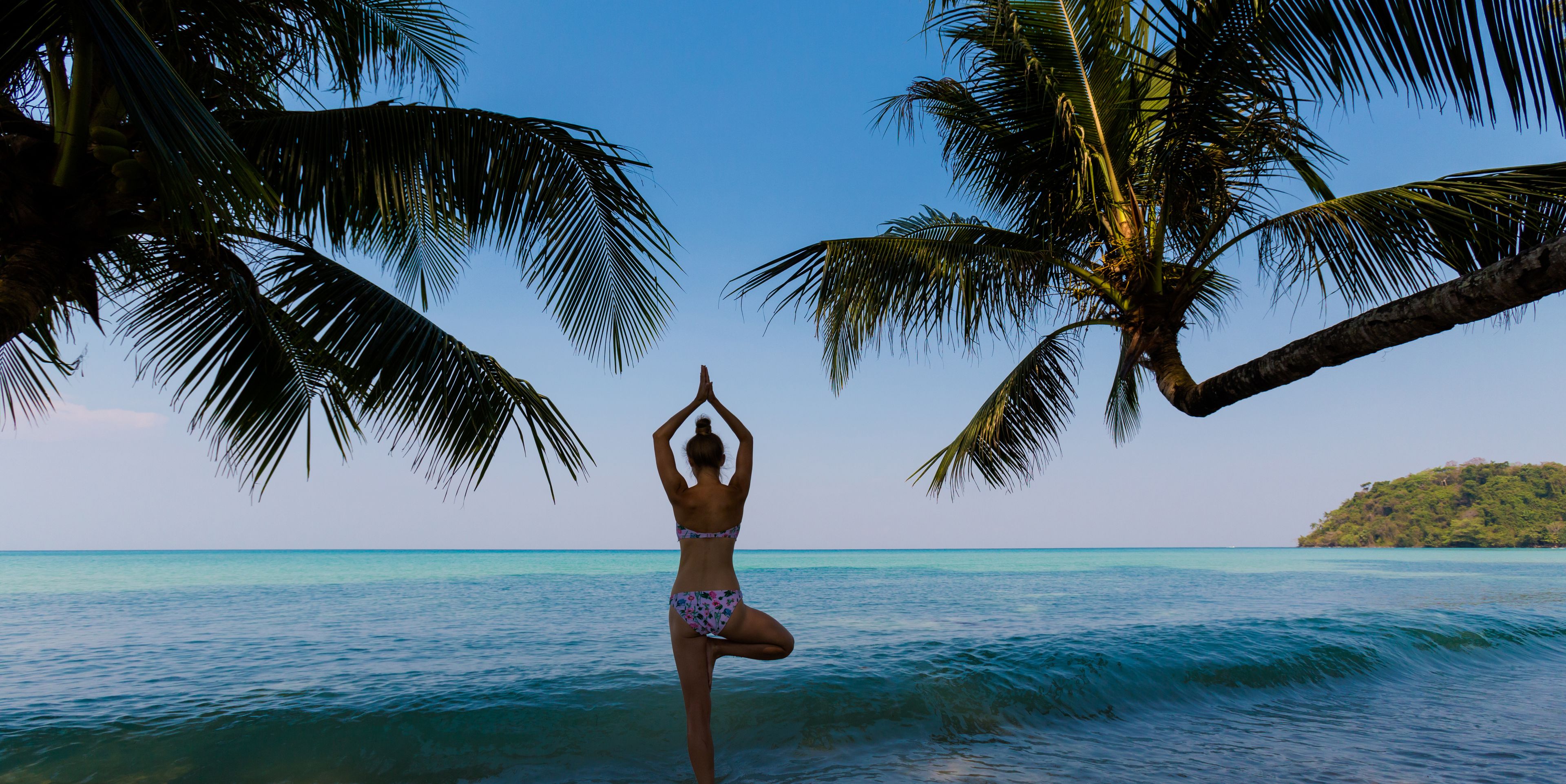 Frau in Baum-Yoga-Pose am Meer 