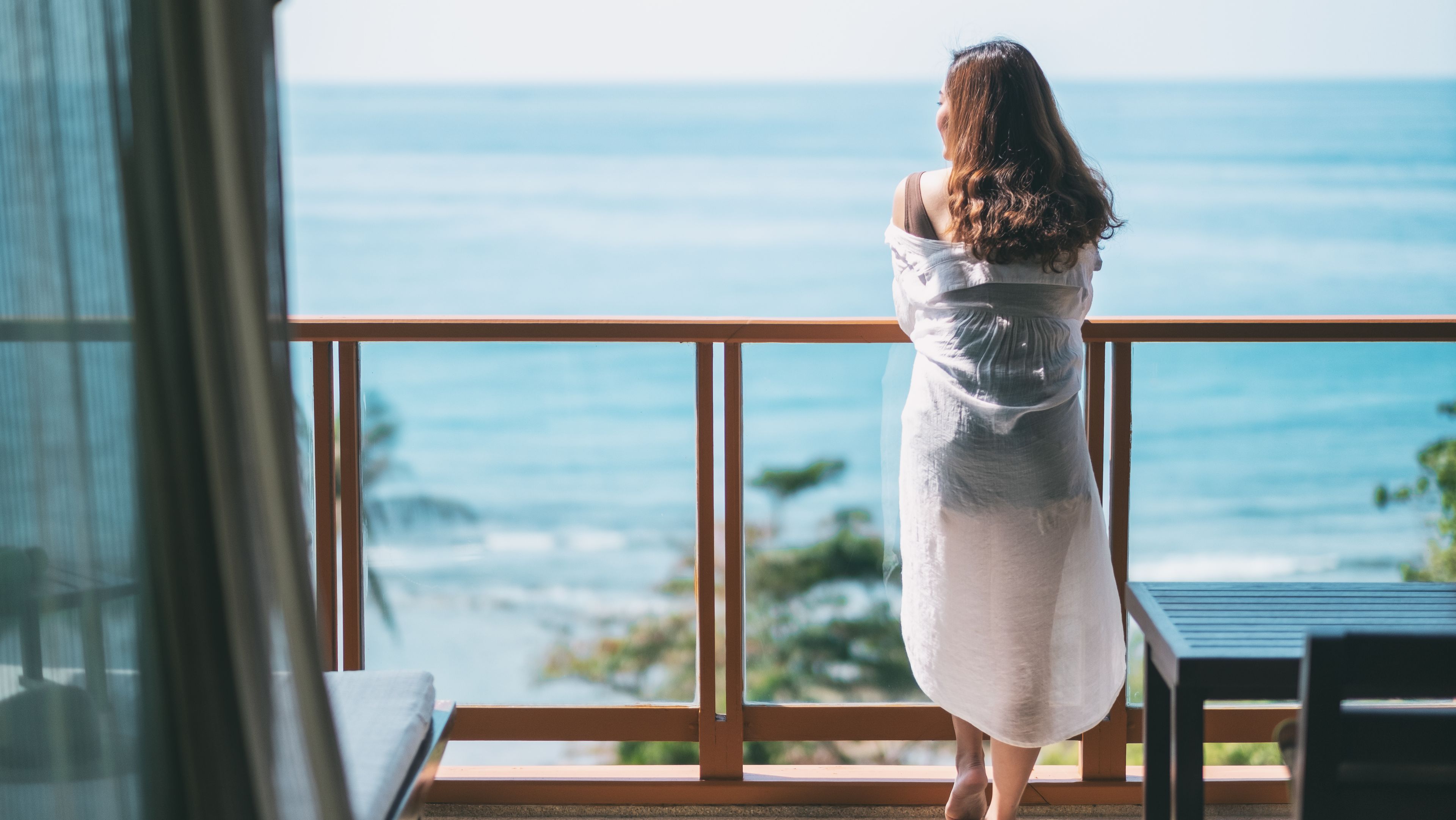 Une femme se tient sur son balcon et regarde la mer