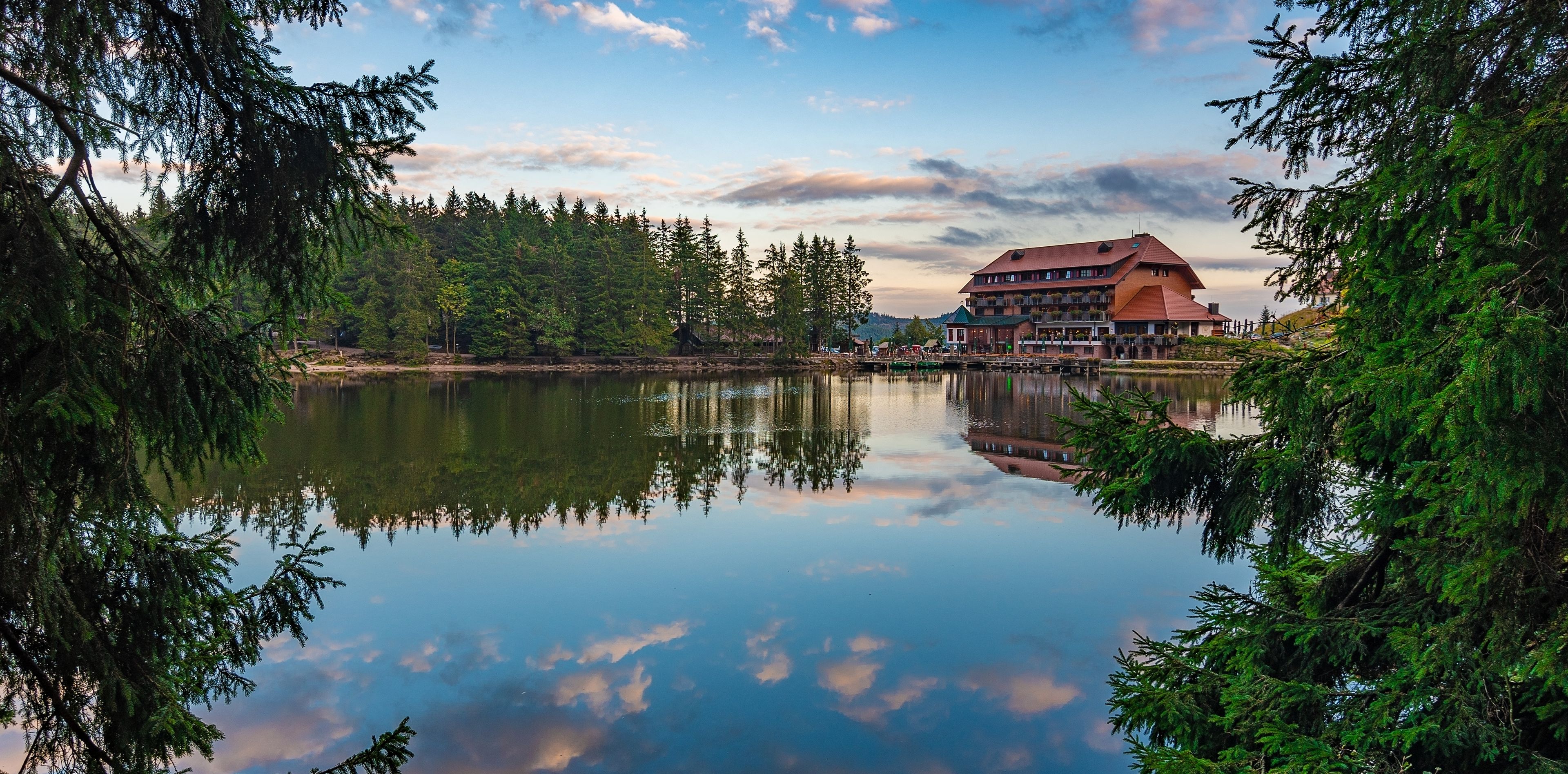 Ein See umrandet von Bäumen und einem Haus 