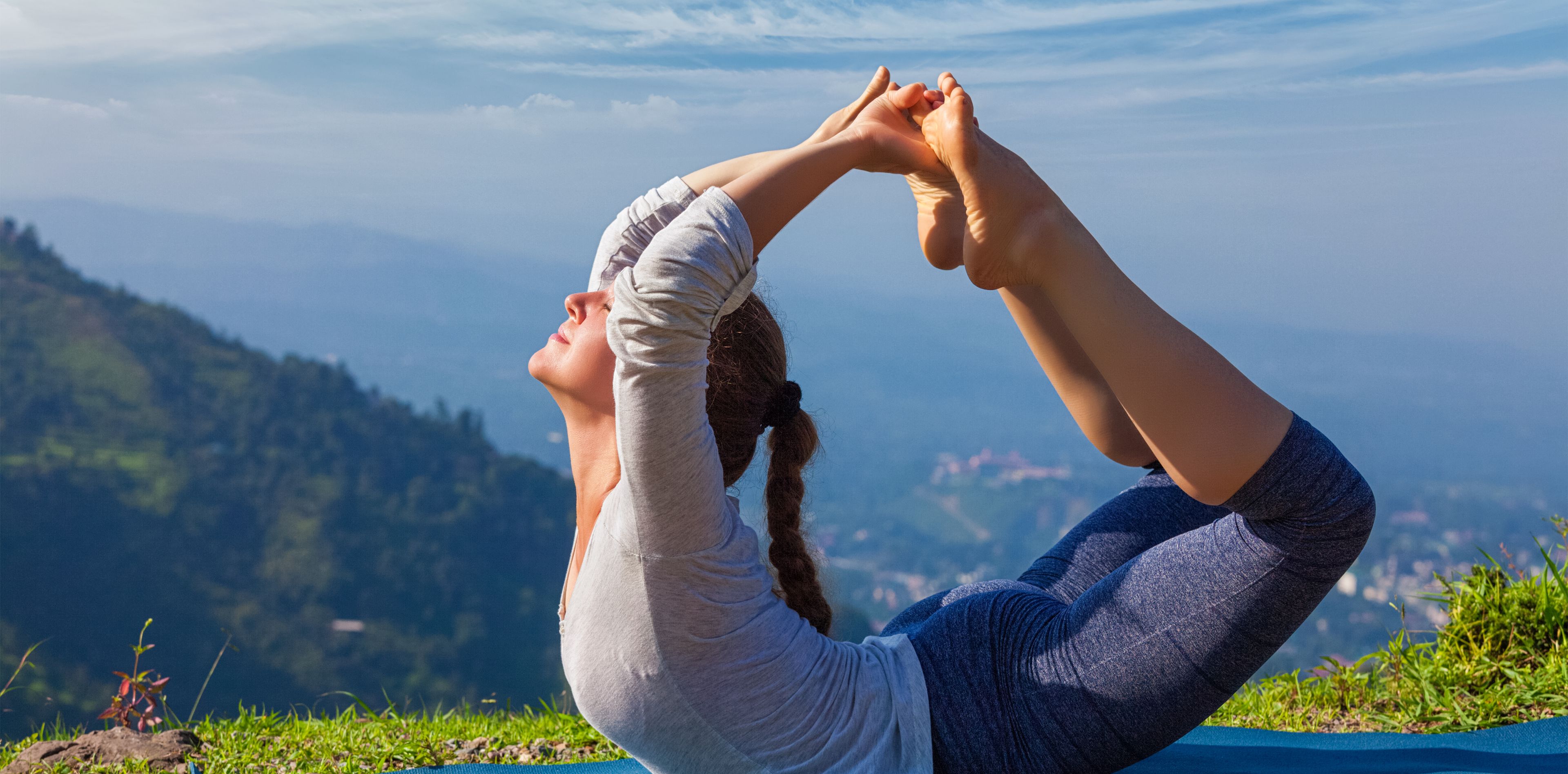 Frau in Yoga Stellung auf dem Gipfel eines Berges
