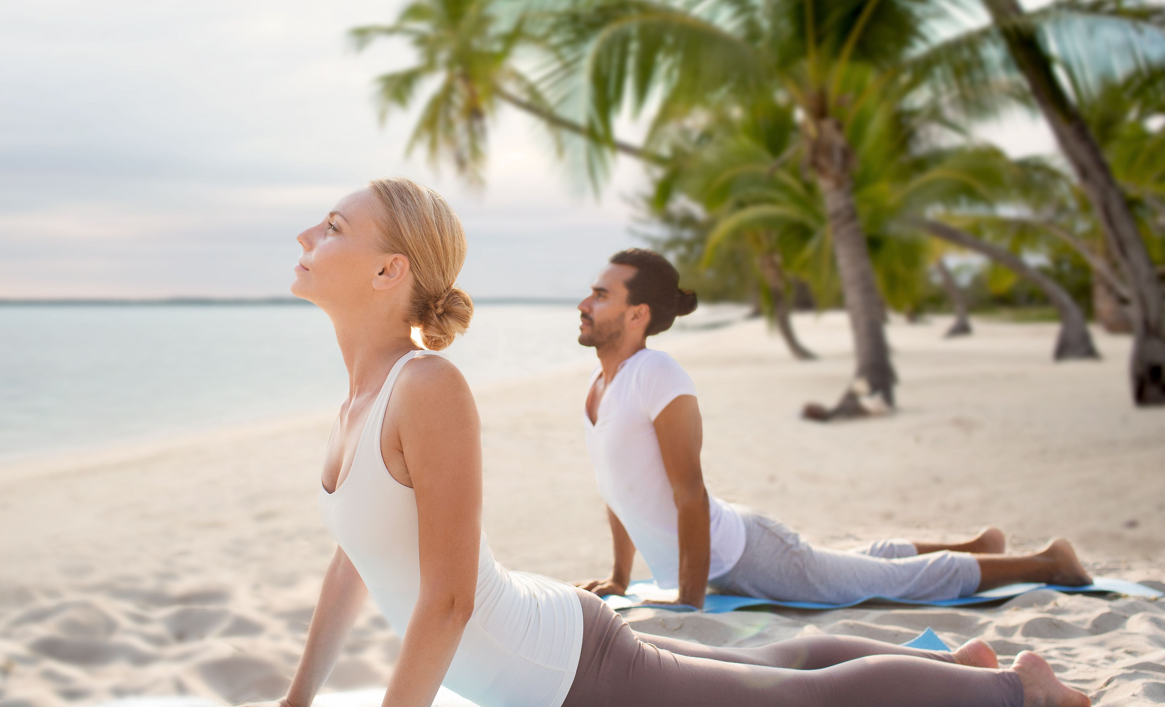 Zwei Menschen beim Yoga in Kobra Stellung am Strand