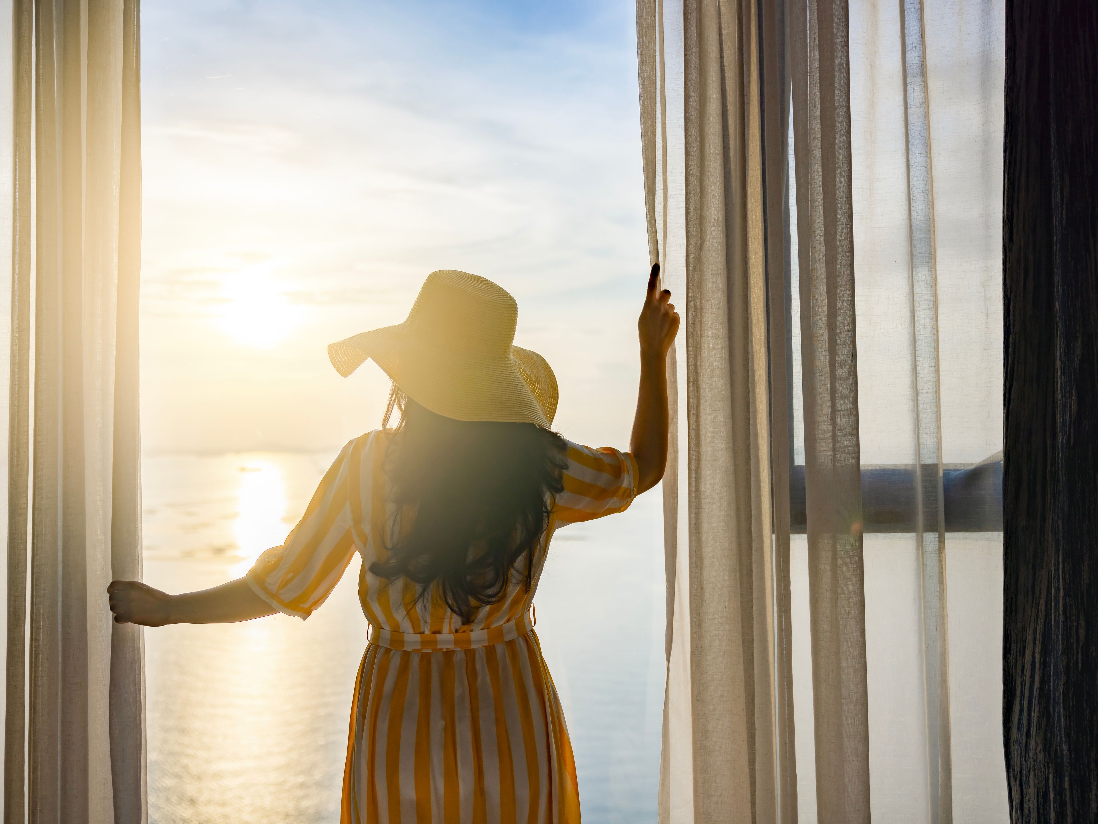 Eine Frau blickt von Ihrem Hotelzimmer auf die Ostsee