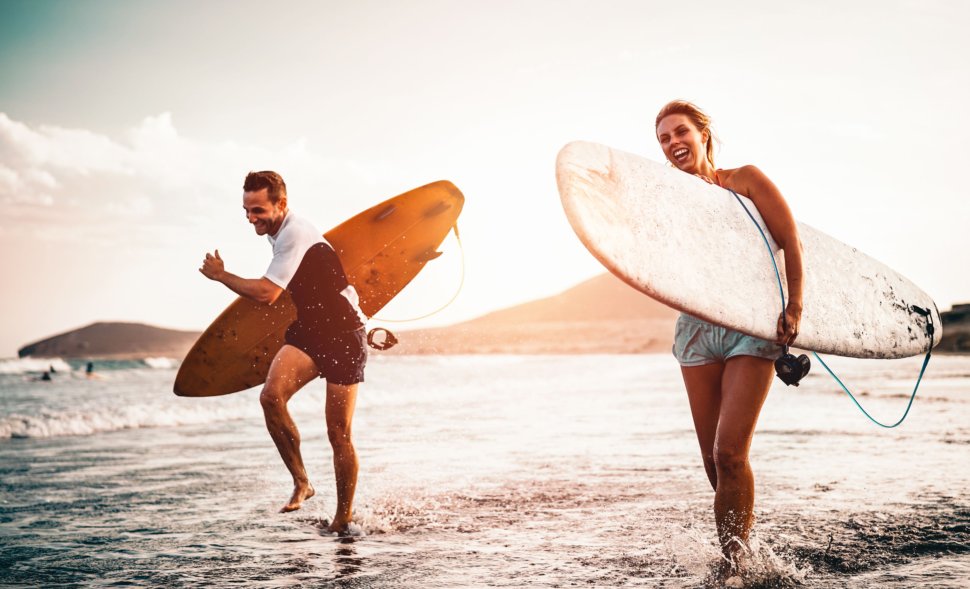 Mann und Frau mit Surfbrettern am Strand