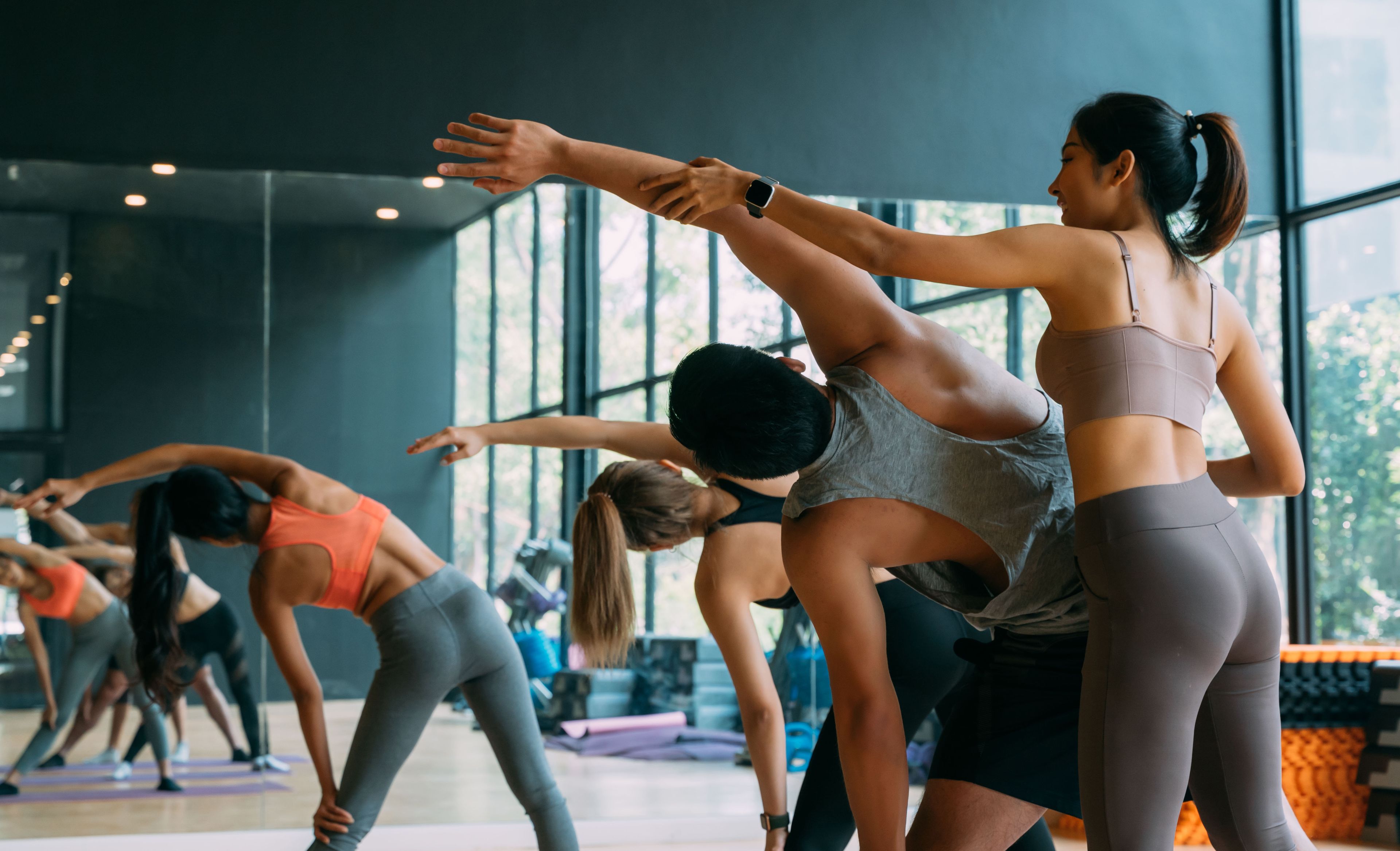Eine Yogalehrerin korrigiert die Yogahaltungen ihrer Schülerinnen.