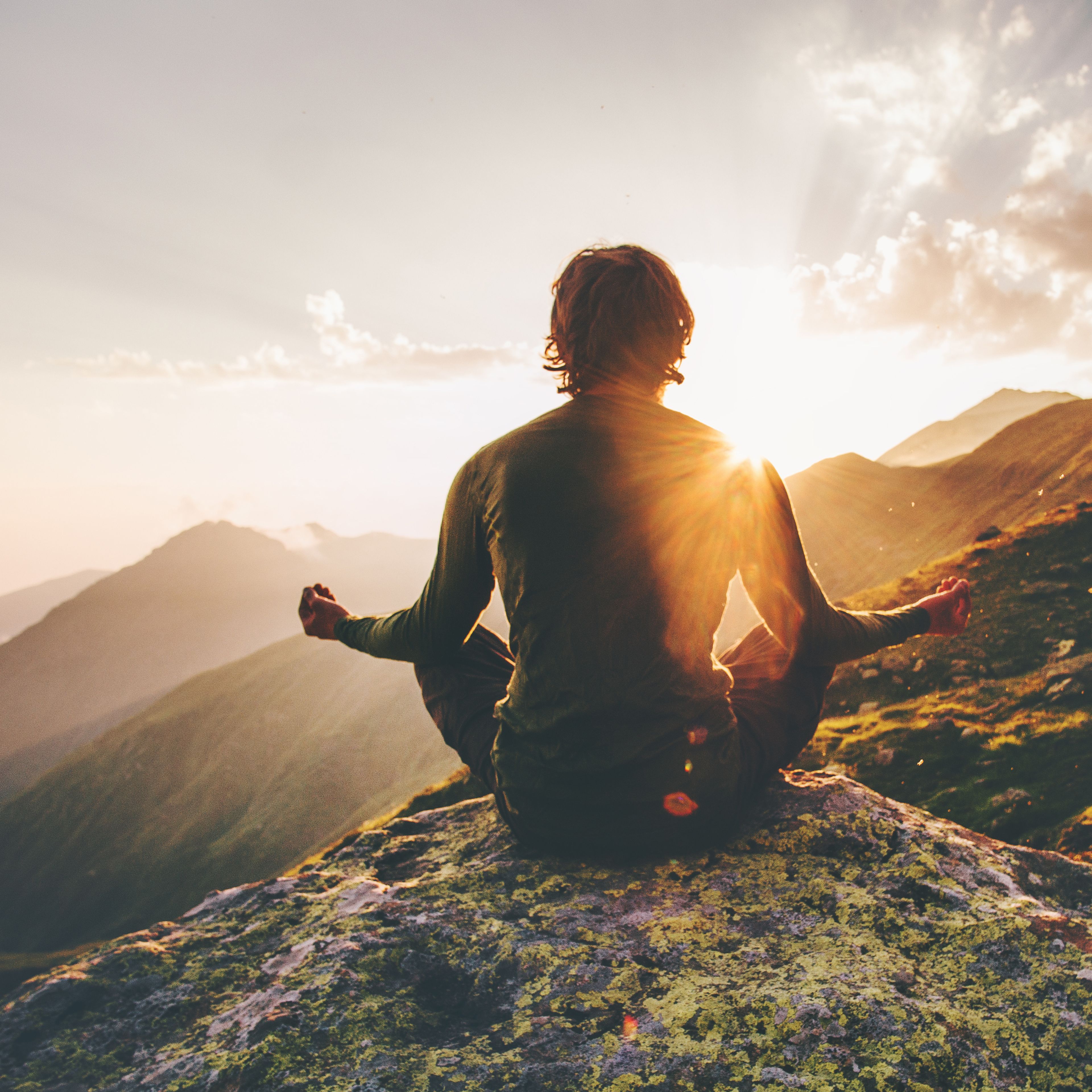 Un hombre medita en una montaña al amanecer