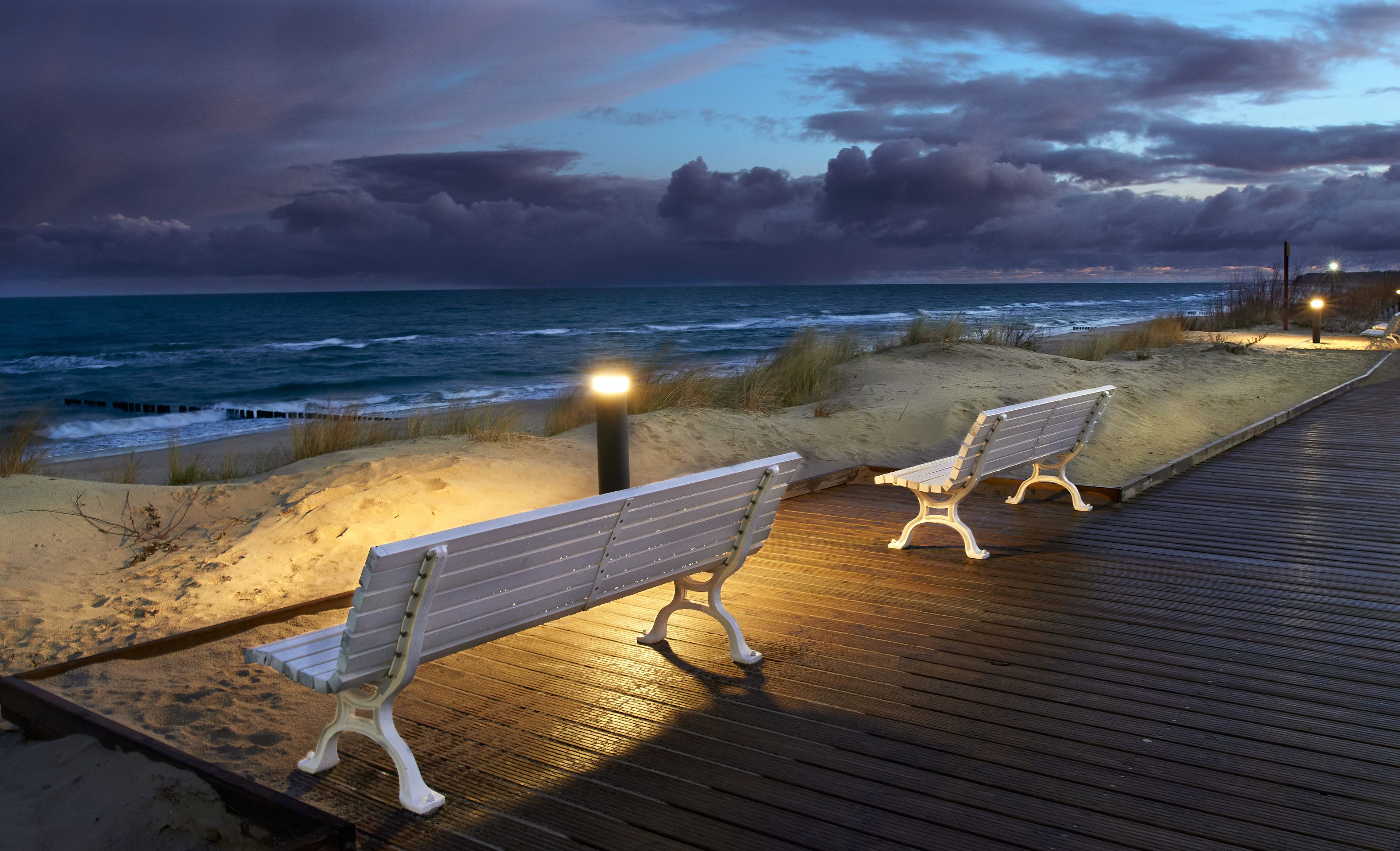 Bänke auf beleuchtete Strandpromenade am Abend