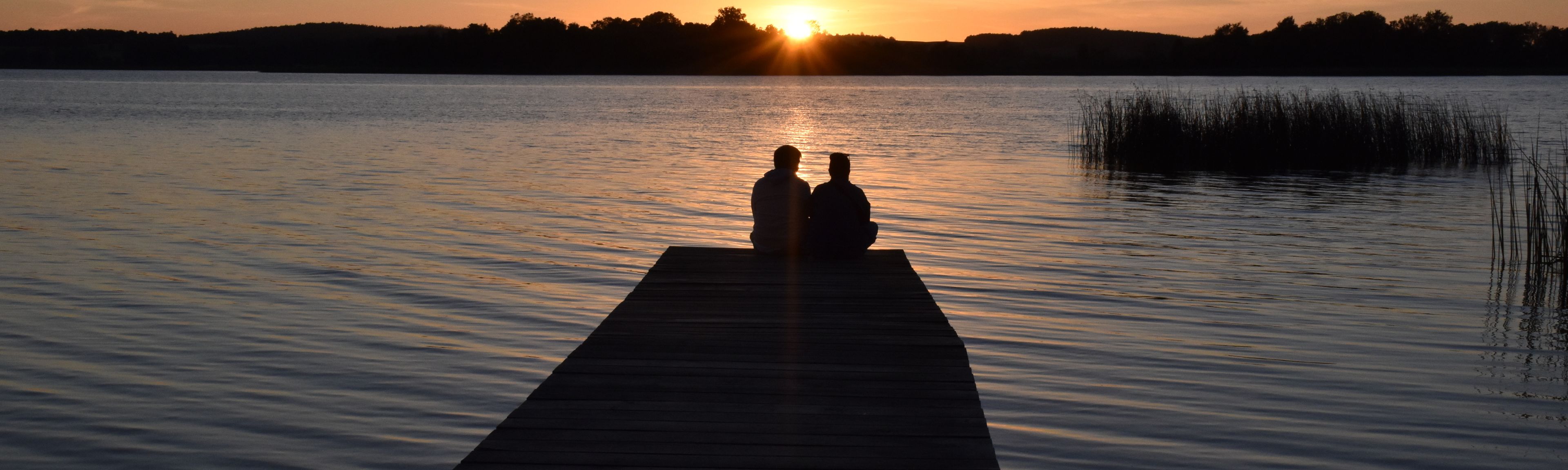 Paar sitz auf einem Steg am Oberuckersee in der Abendsonne