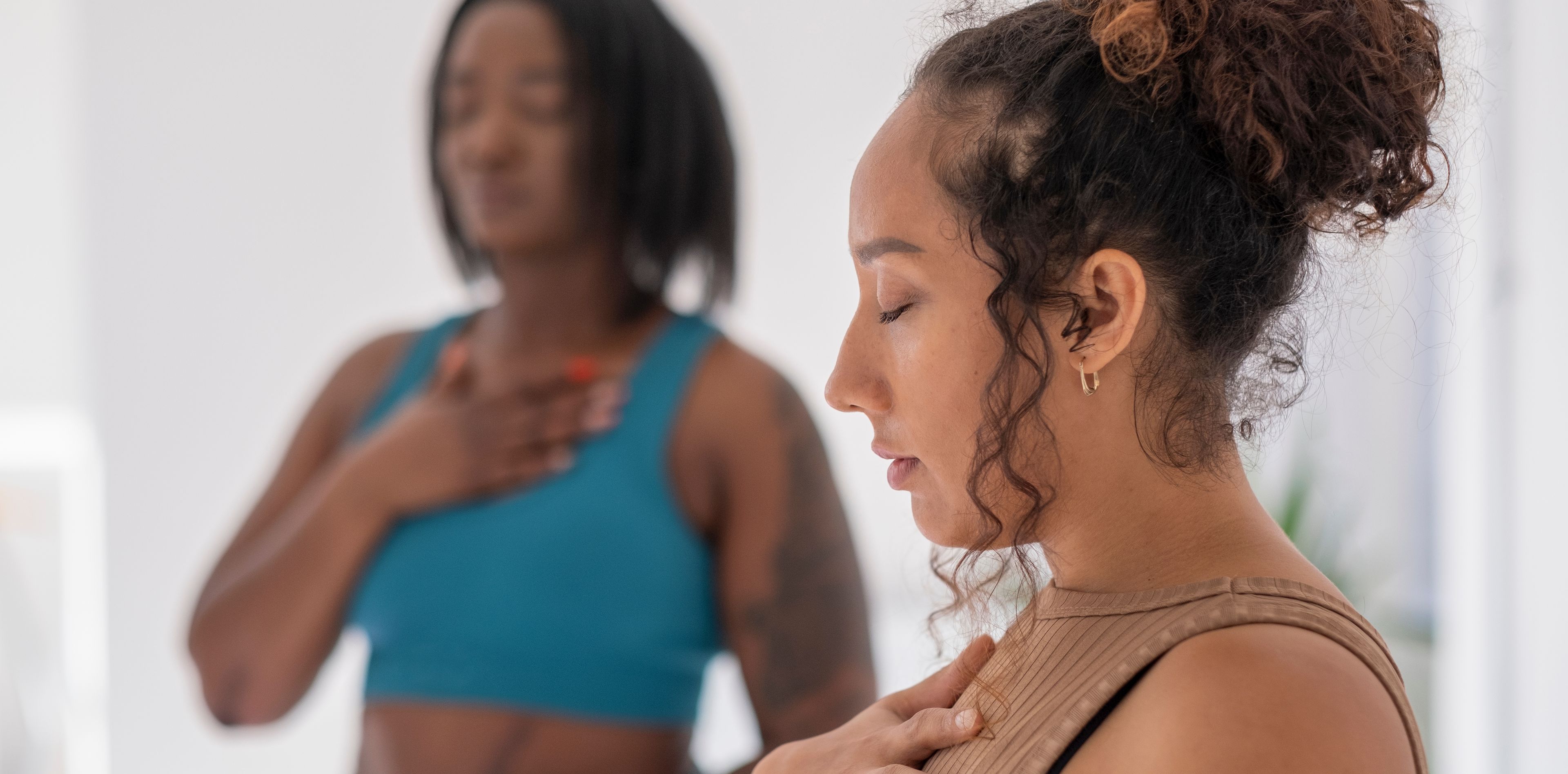 Zwei Frauen praktizieren Pranayama in hellem Yoga Studio