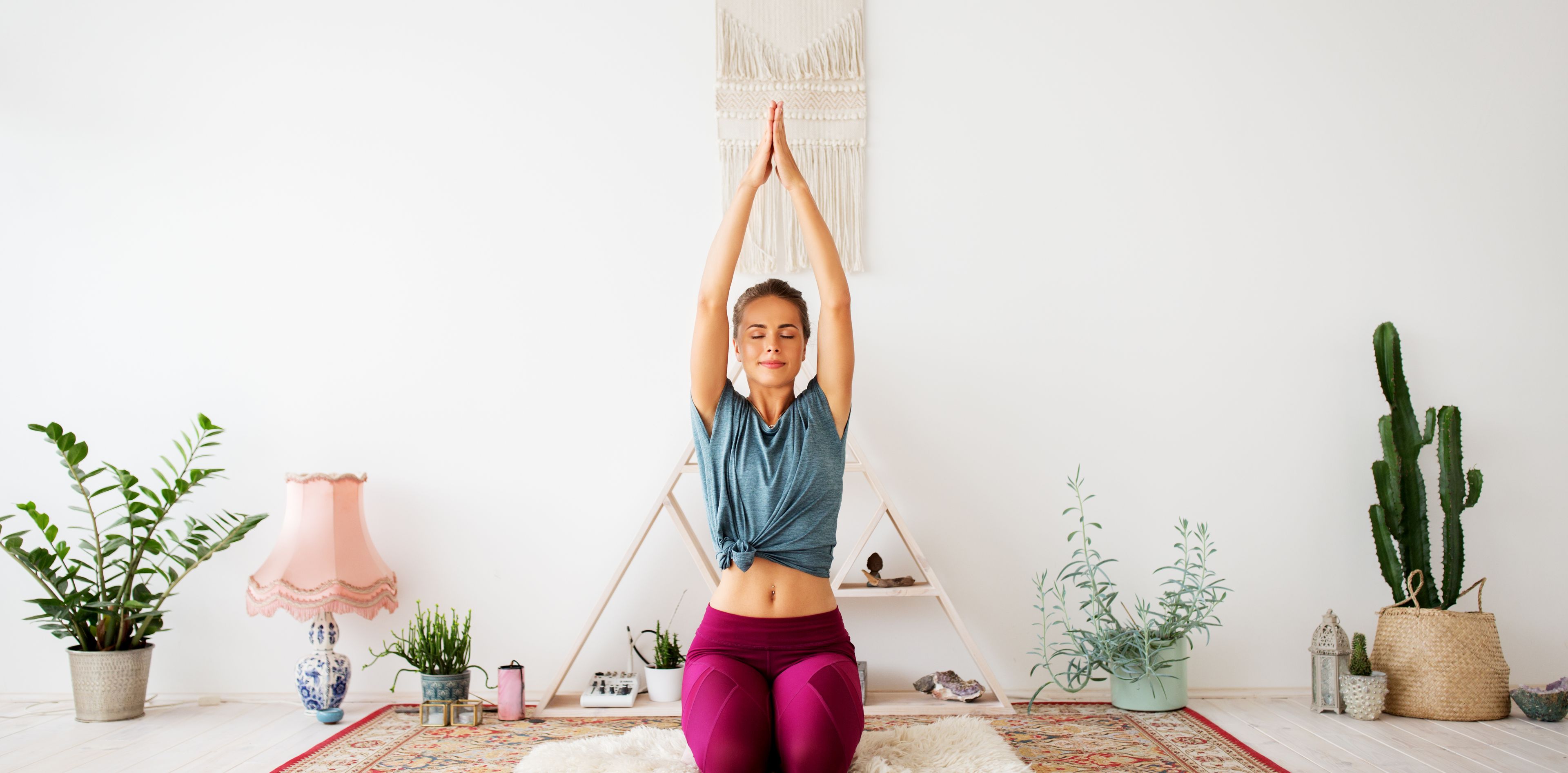 Frau in Yogastellung in einem im Boho-Stil eingerichteten Raum