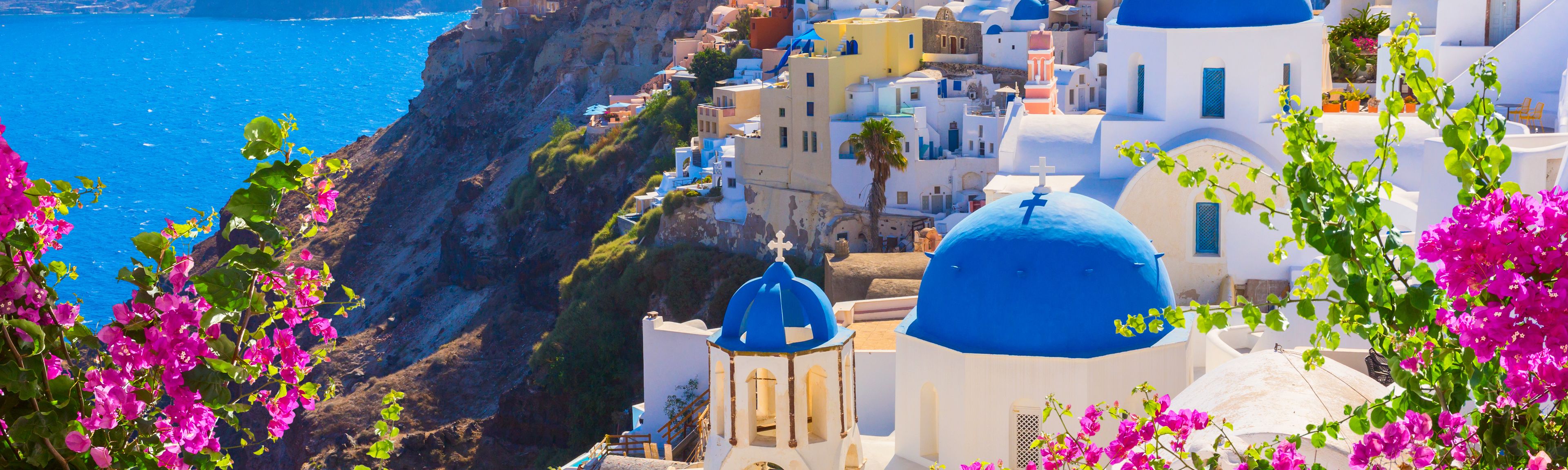 Weiße Häuser mit blauen Dächern und dem Meer im Hintergrund zeigen das typische Griechenland