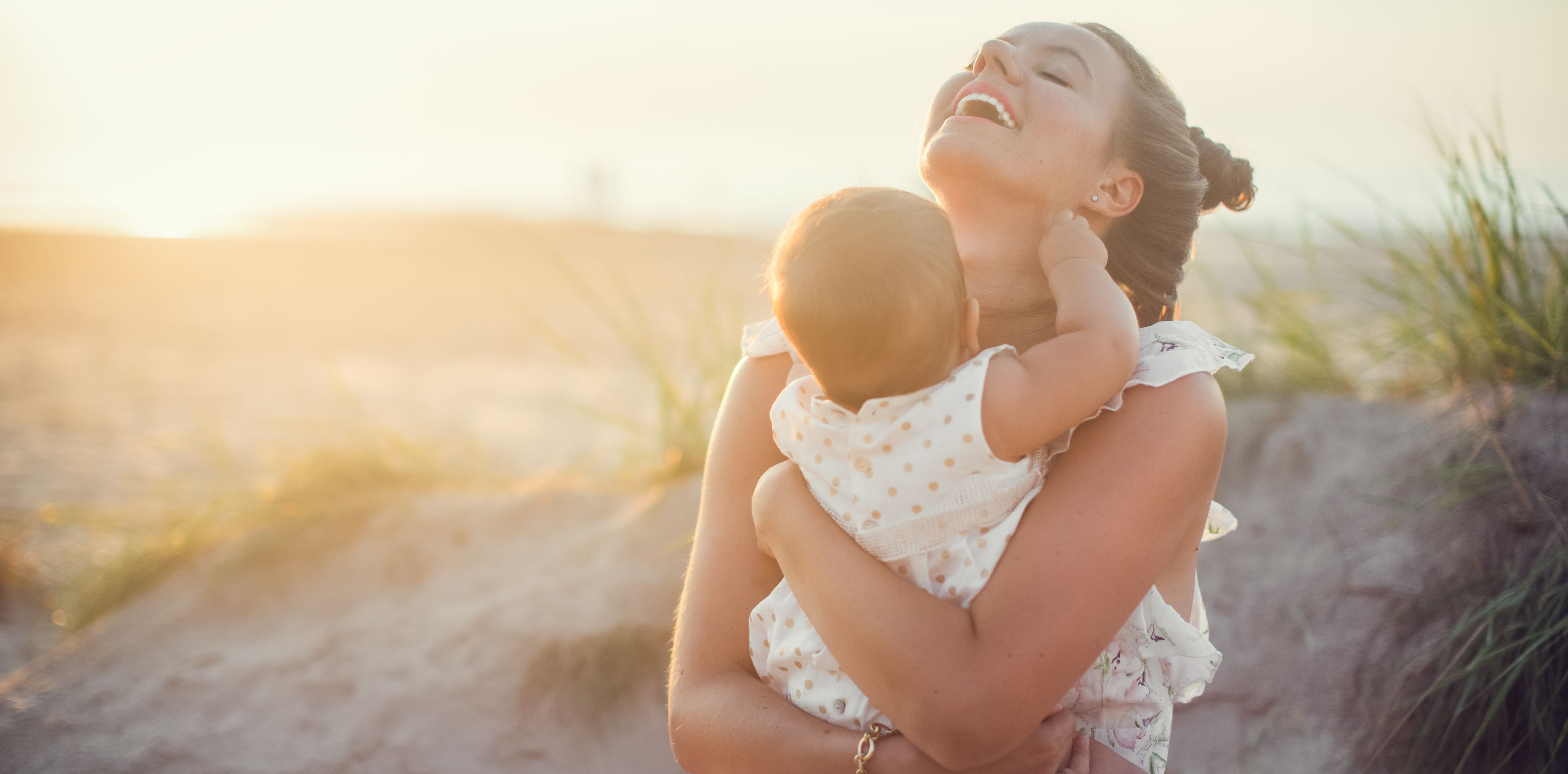 Frau mit Baby auf dem Arm am Strand