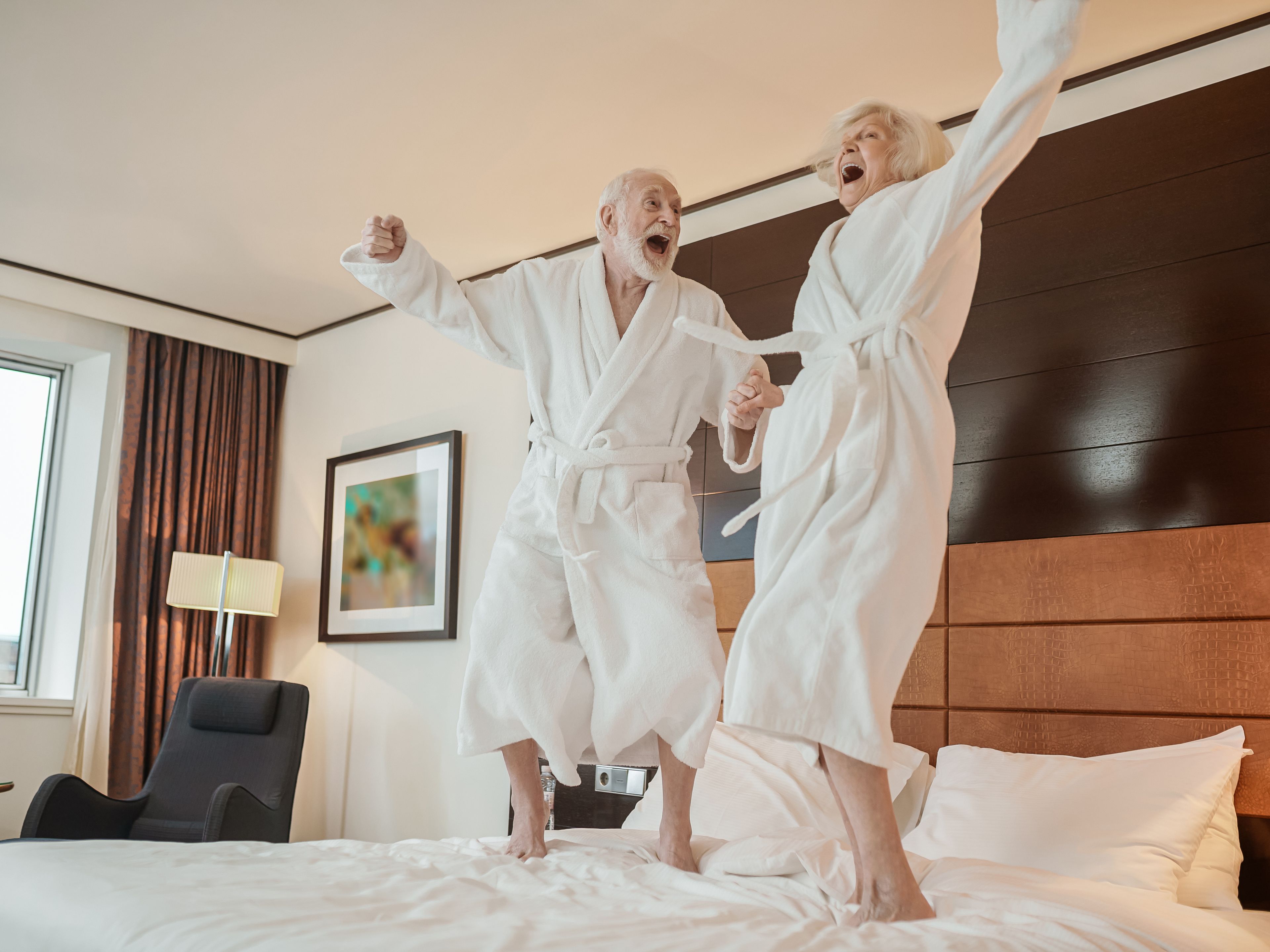Senioren Paar springt auf dem Hotelbett