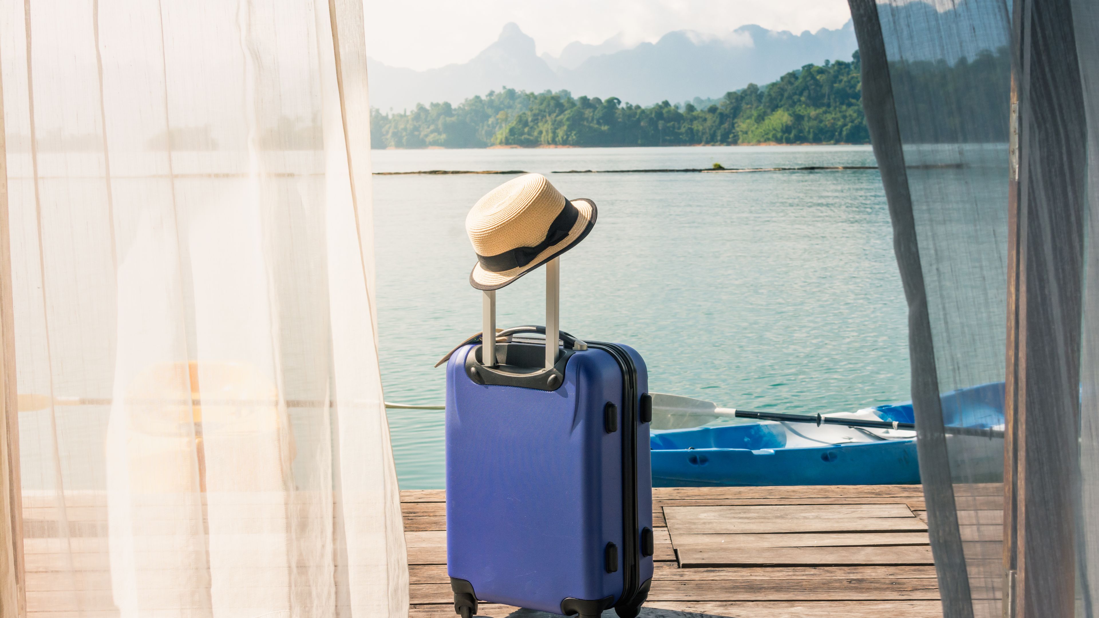 A suitcase stands on a jetty and in the background is a large lake