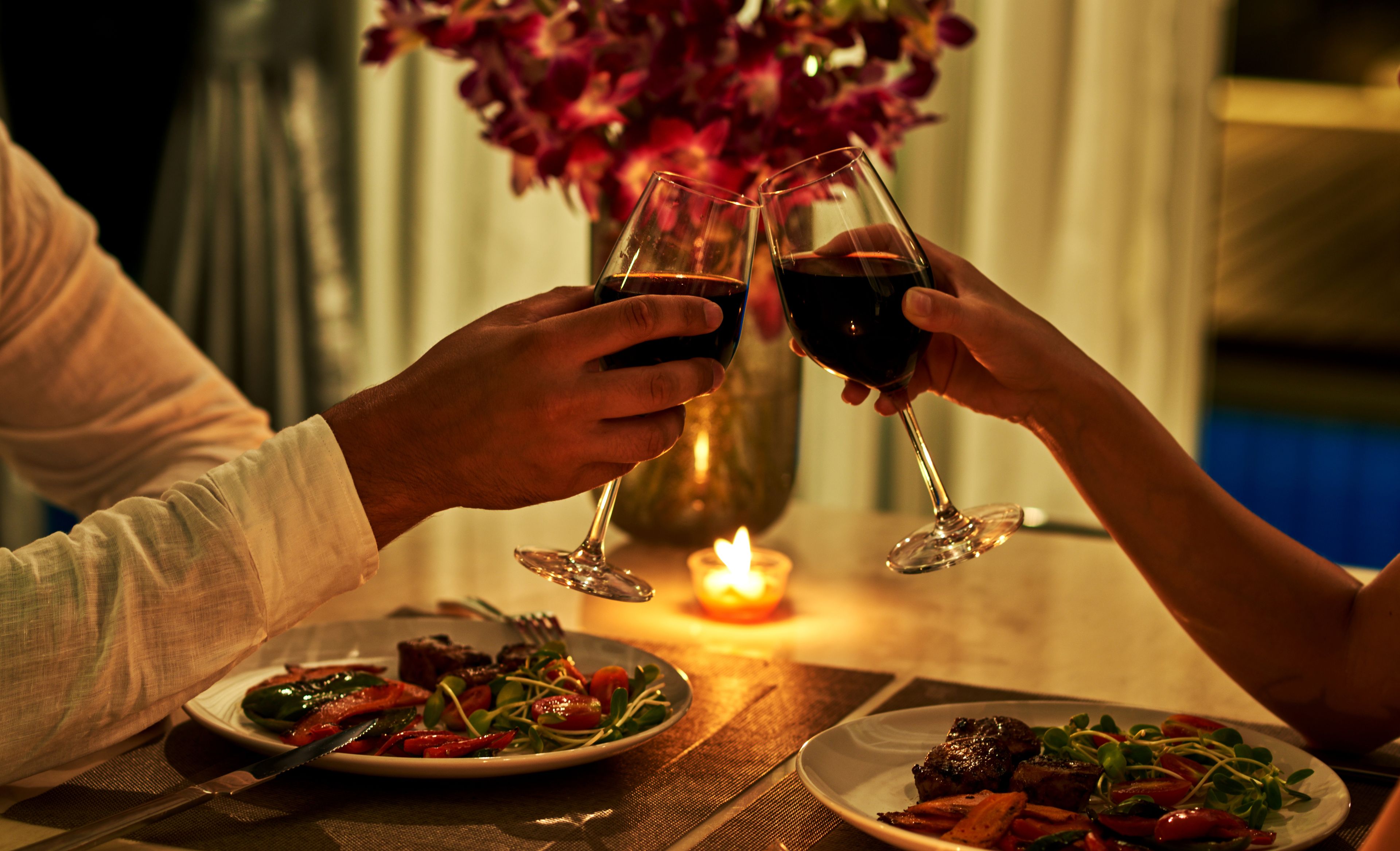 Mann und Frau stoßen mit Wein an bei Dinner im Kerzenschein