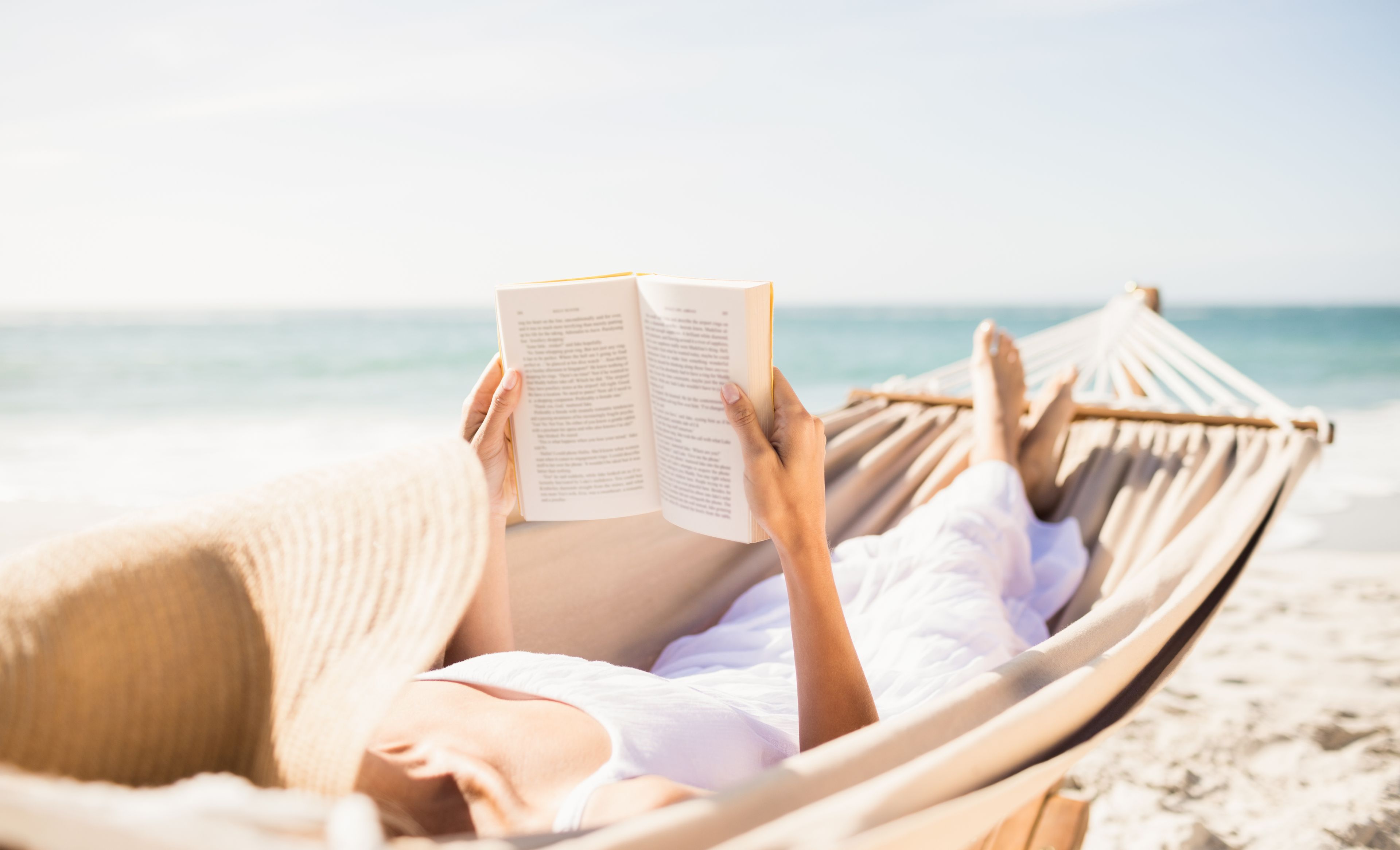Una mujer leyendo en una hamaca en la playa