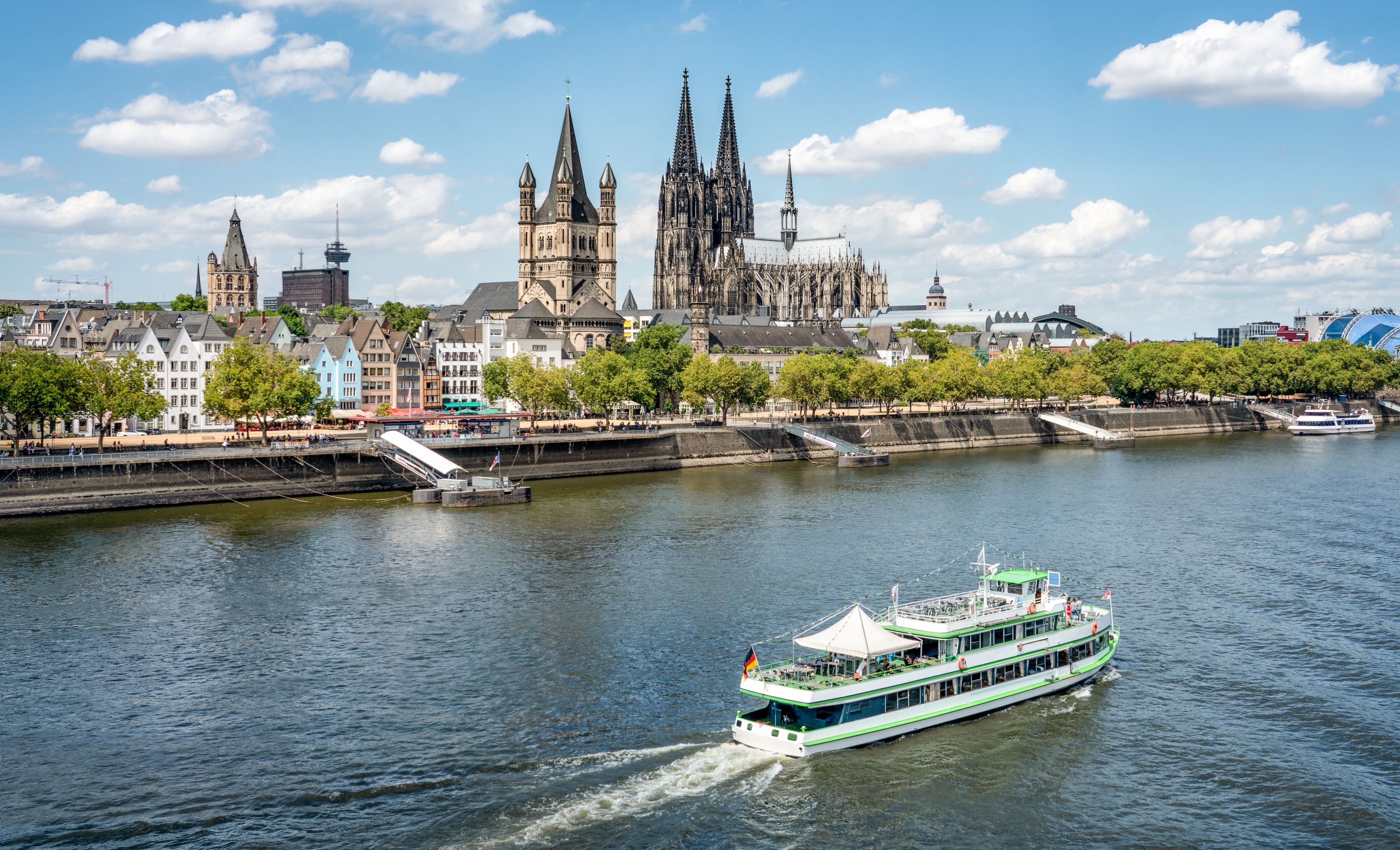 Kleines touristisches Schiff auf dem Rhein mit Dom im Hintergrund
